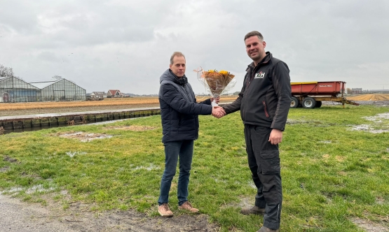 Coach overhandigt bloemen aan bloembollenkweker Ron van Haaster